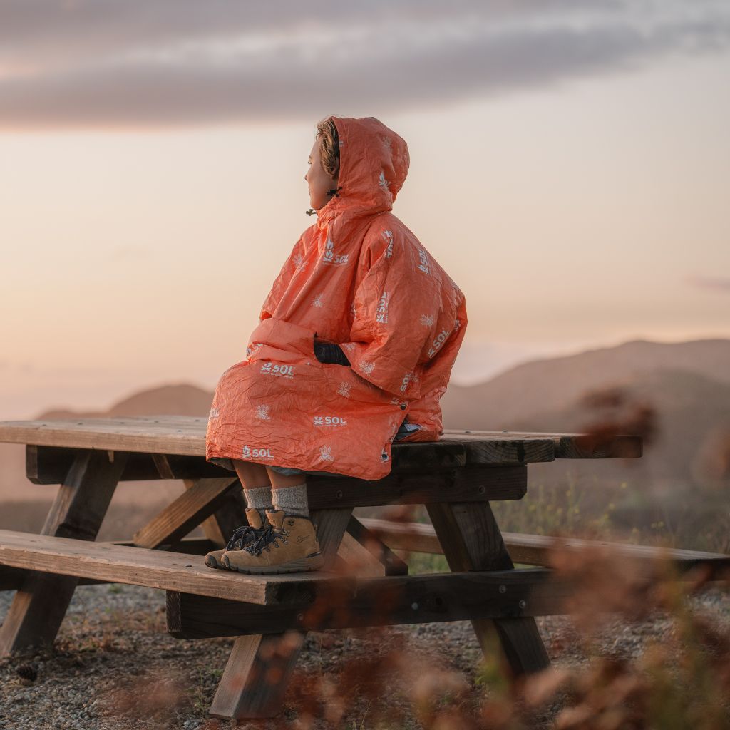 Escape Insulated Poncho woman sitting on picnic table in poncho outdoors