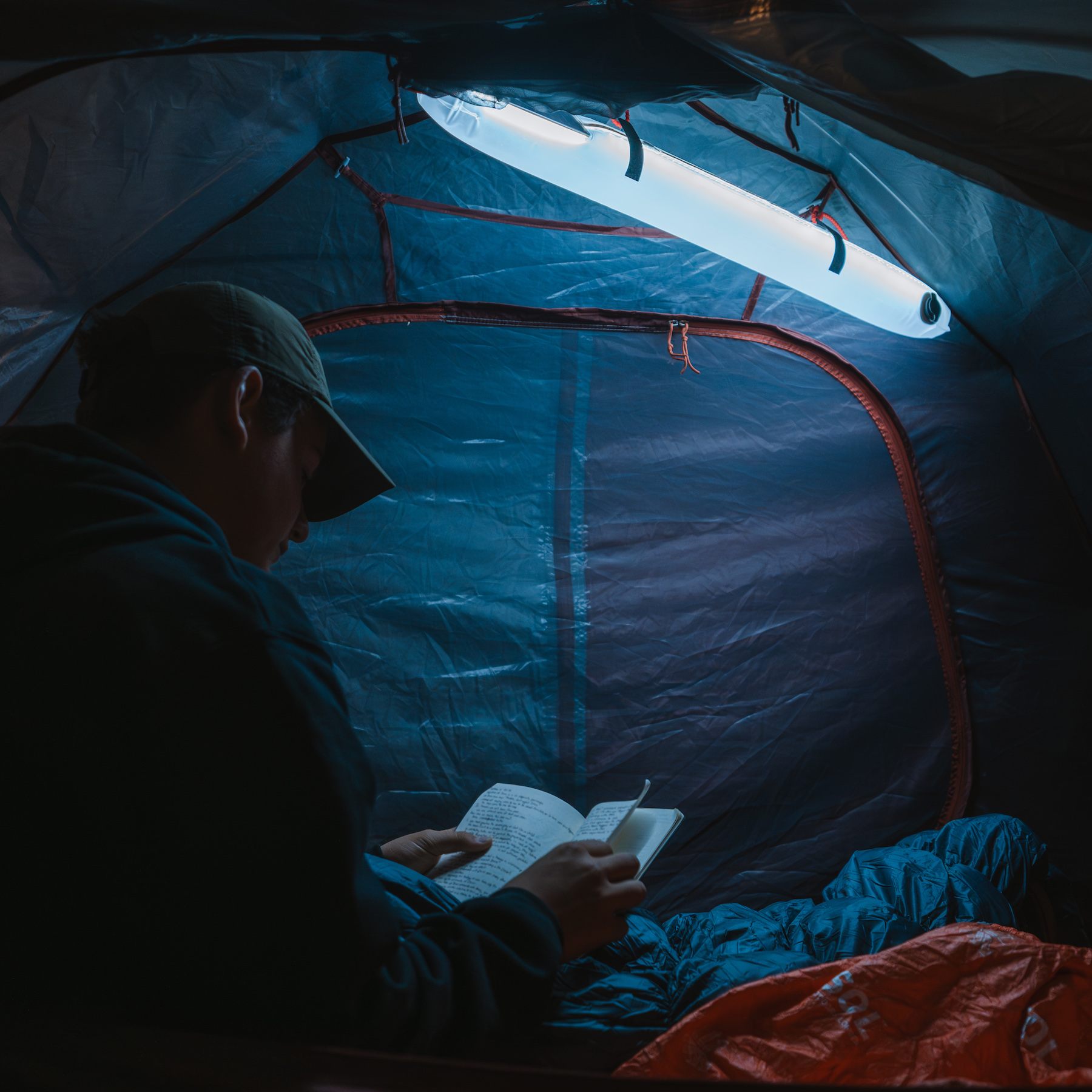 Man reading in a tent, illuminated by the Solar Beam