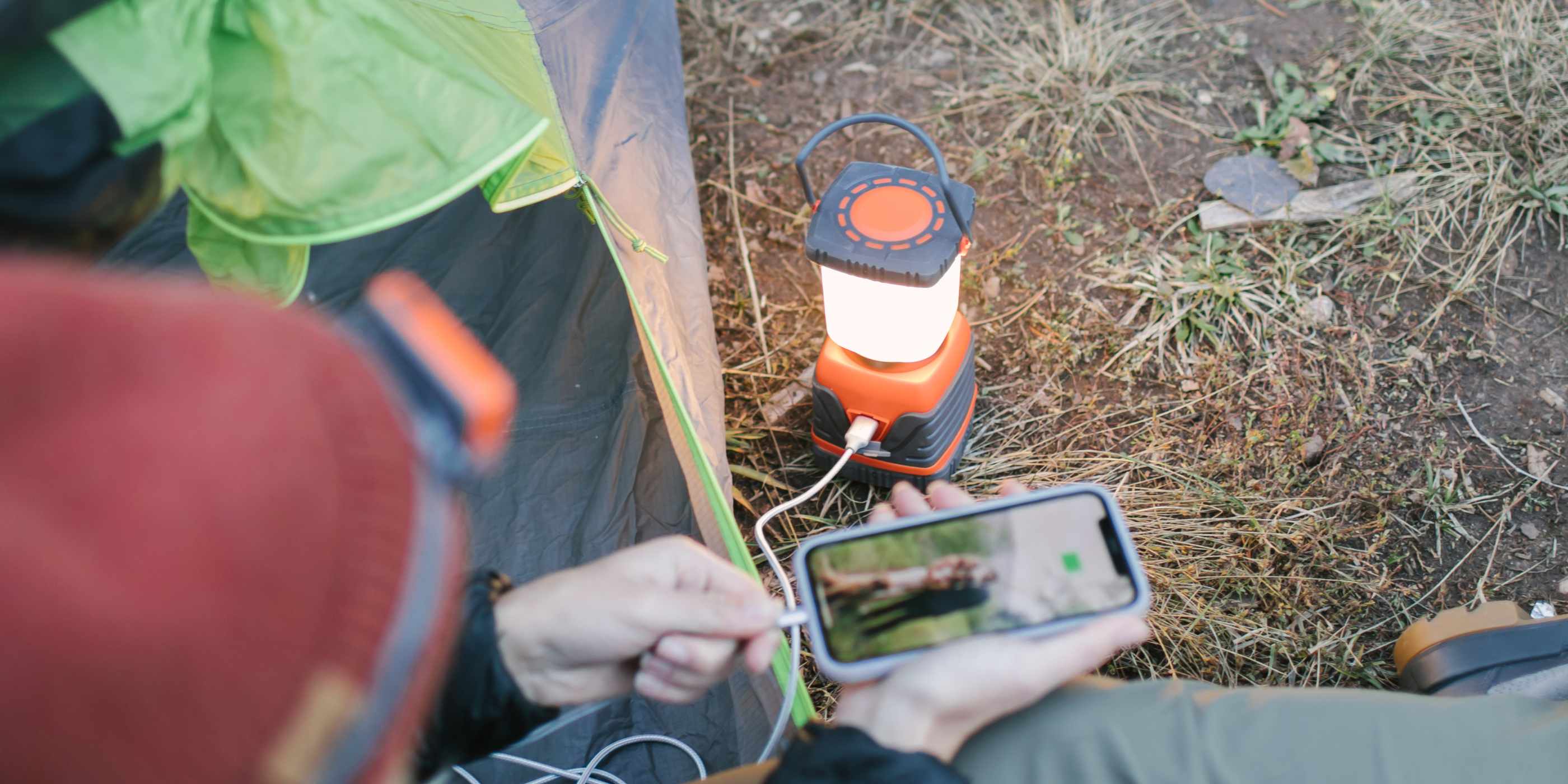 Woman Sitting in Tent Charging Phone with SOL Rechargeable Camp Lantern Power Bank