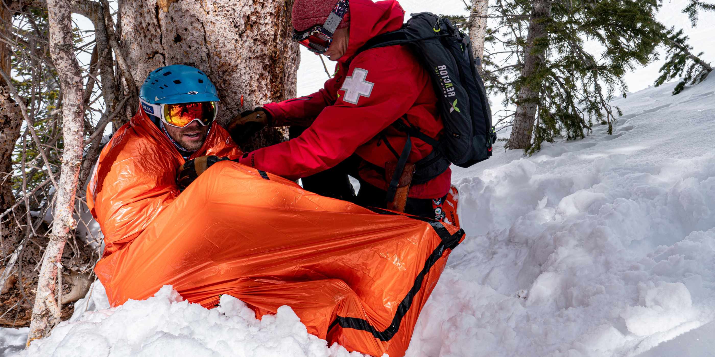 Ski Patrol Wrapping Injured Skier in Orange SOL Emergency Bivvy in Snow