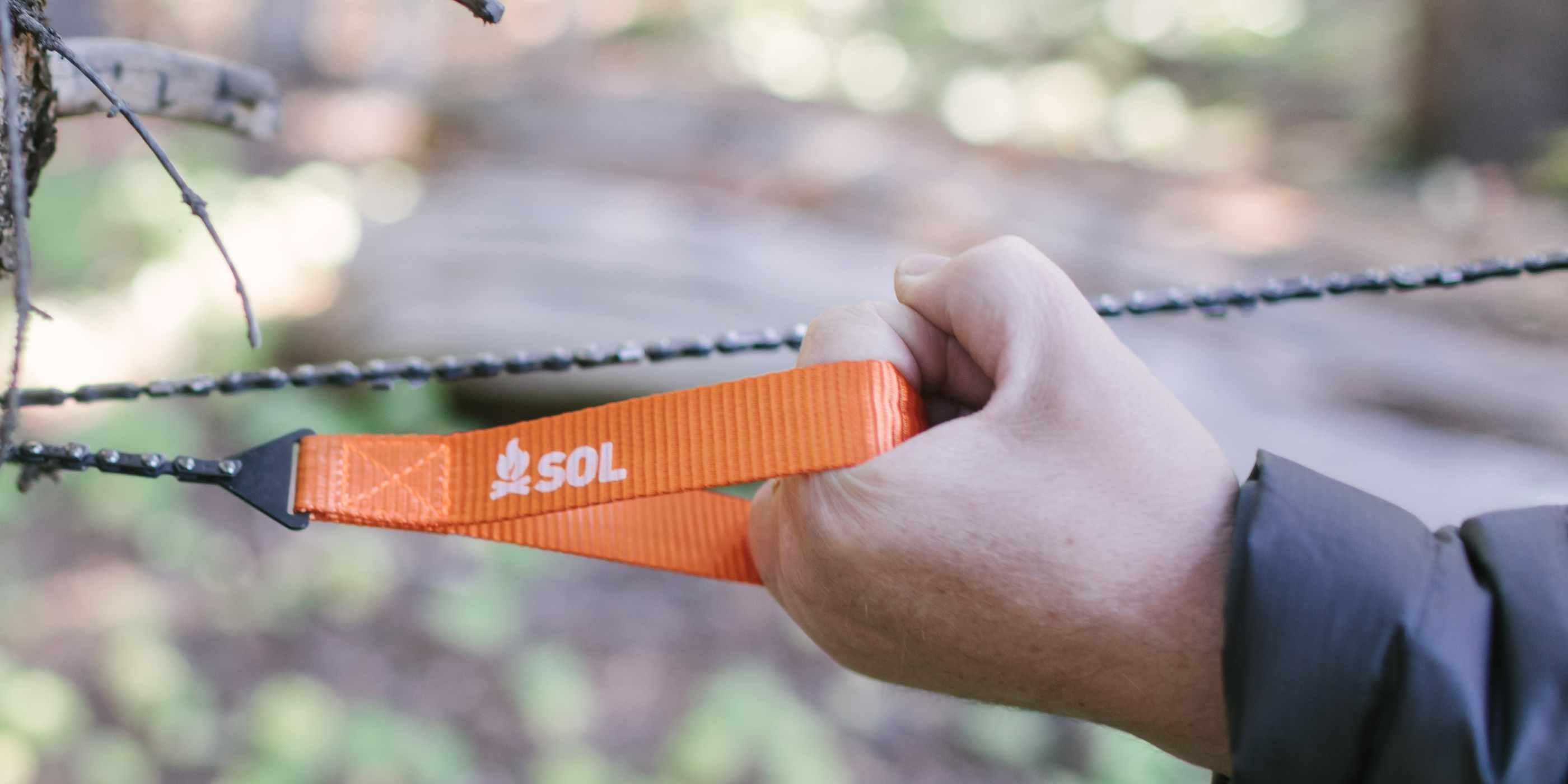 Hands Using Pocket Chain Saw on Tree