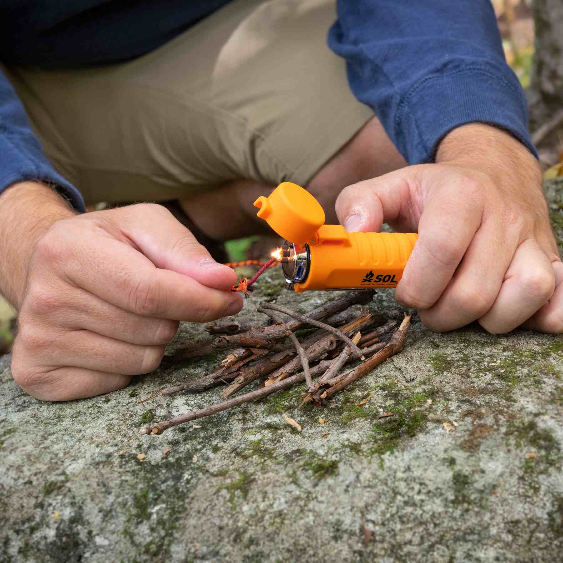 Person Holding SOL Fuel Free Lighter Lighting Tinder Cord on Rock