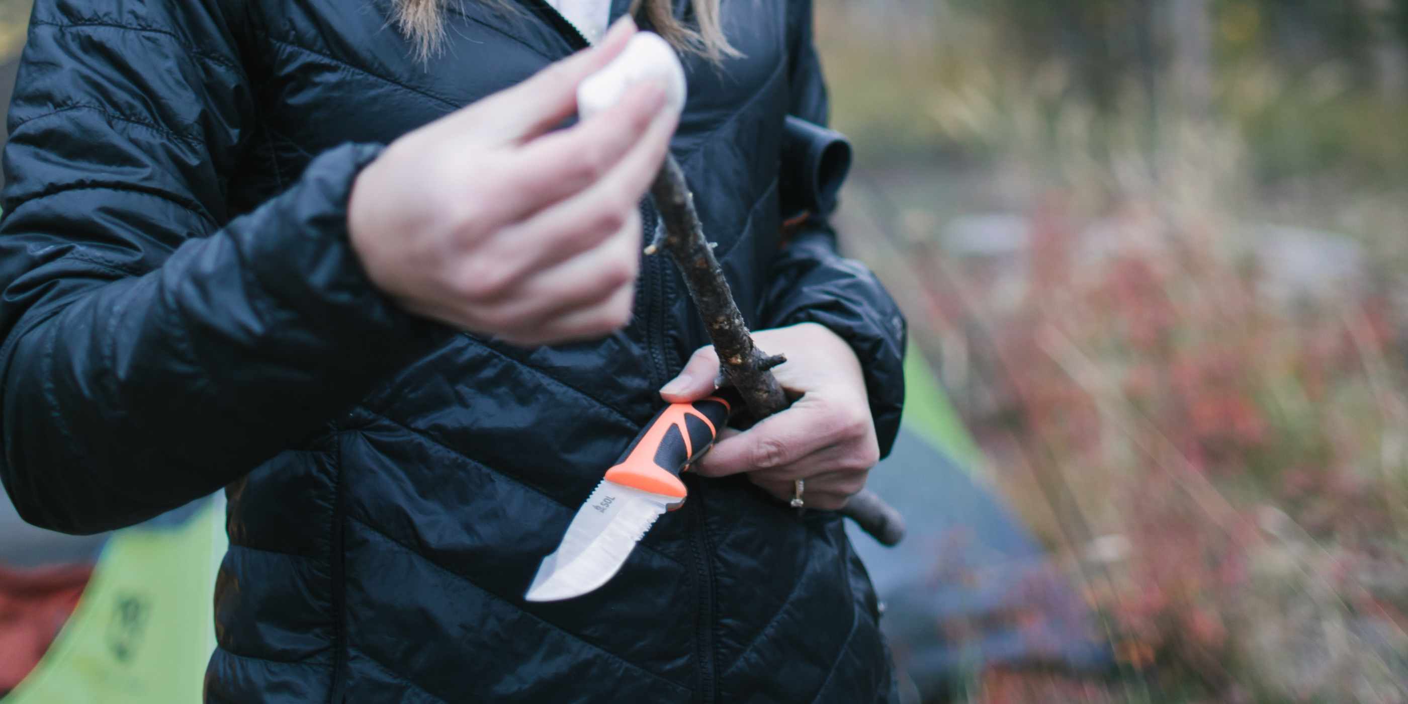 Person in Black Jacket Holding SOL Stoke Field Knife in Hand with Stick