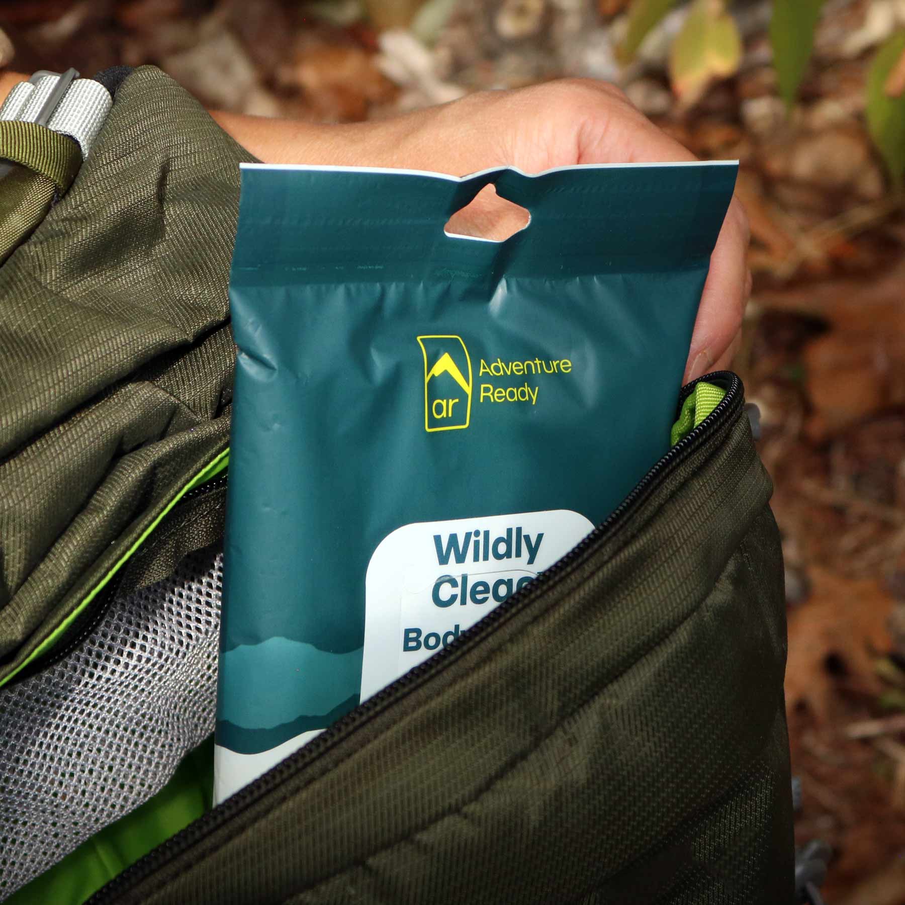 A Wildly Clean Body Wipes packaging being pulled out from inside a backpack.