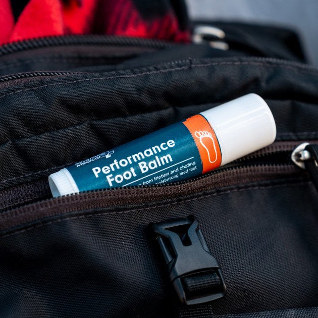 performance foot balm partially inside of backpack