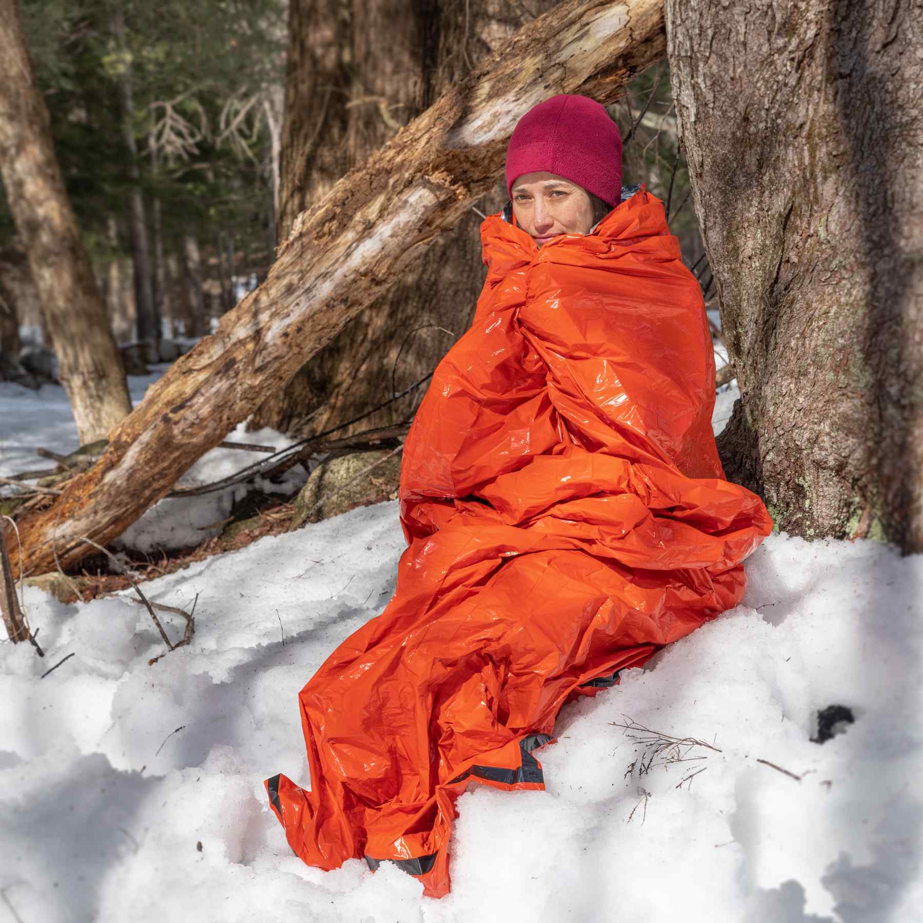 Emergency Bivvy with Rescue Whistle - Orange woman wrapped in bivvy sitting on snow