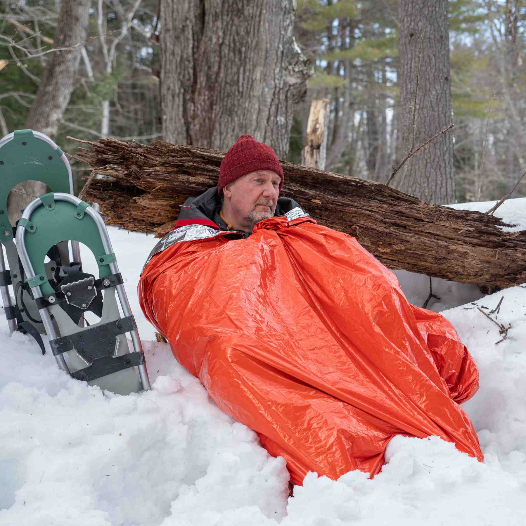 Emergency Bivvy XL w/ Rescue Whistle man wrapped in bivvy leaning on tree in snow with snowshoes next to him