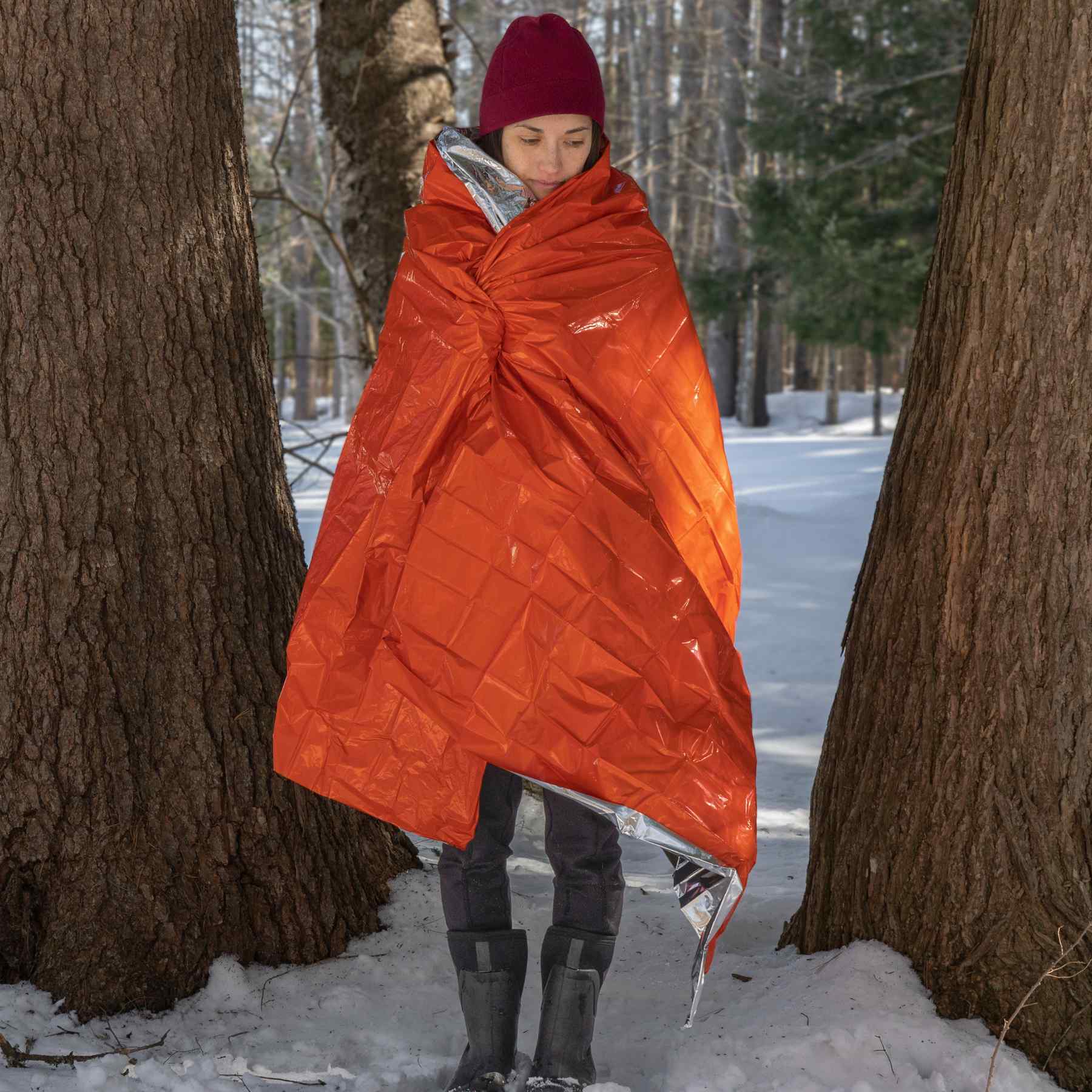Emergency Blanket woman wrapped in blanket with large trees around her