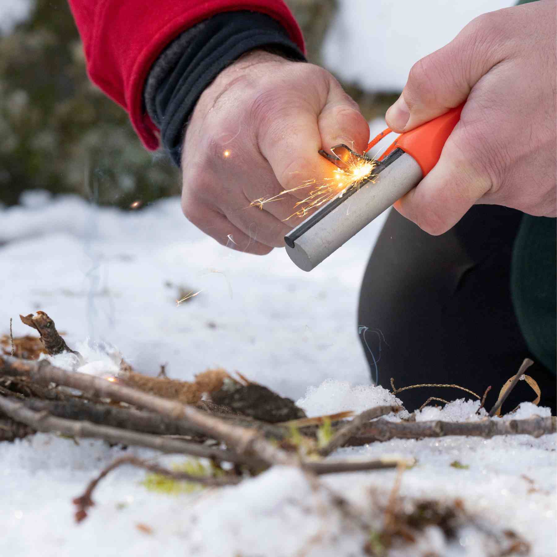 Mag Striker with Tinder Cord creating sparks over twigs on snow