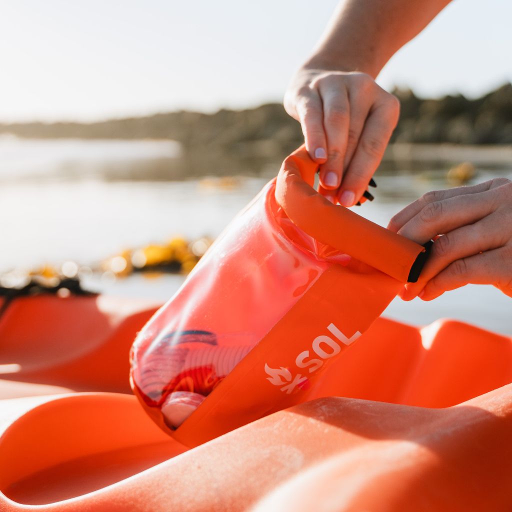 Adventure Ready Survival Kit closing kit on orange kayak on water