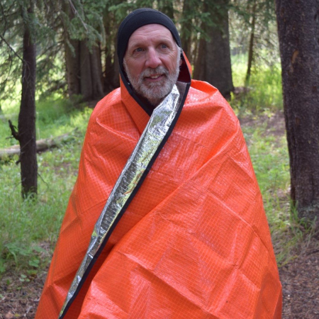 All Season Blanket man in black hat wrapped in blanket in woods