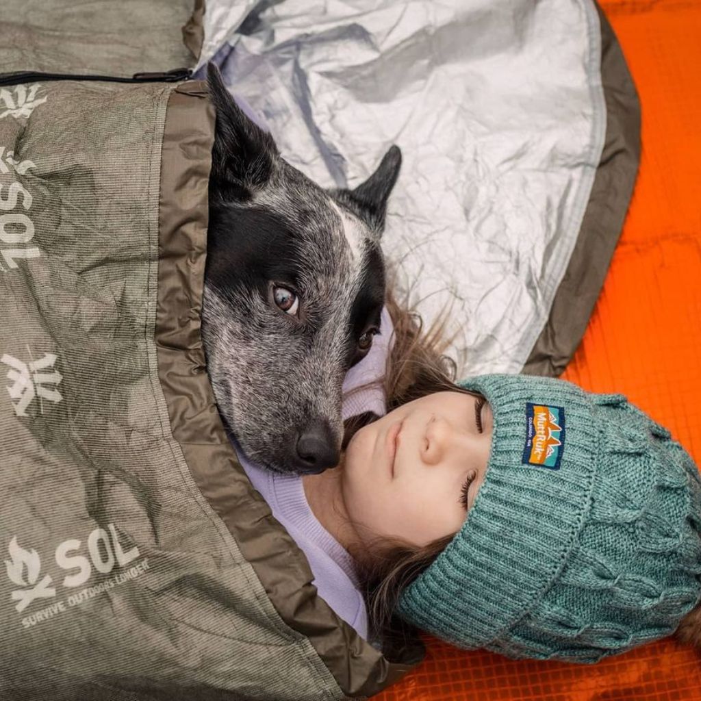 Escape Bivvy OD Green child in green hat sleeping in bivvy with black and white dog