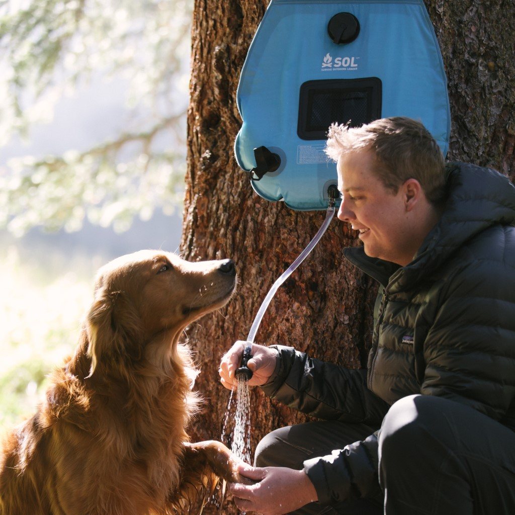 Solar Shower 20L hanging on tree with man washing dog's paws