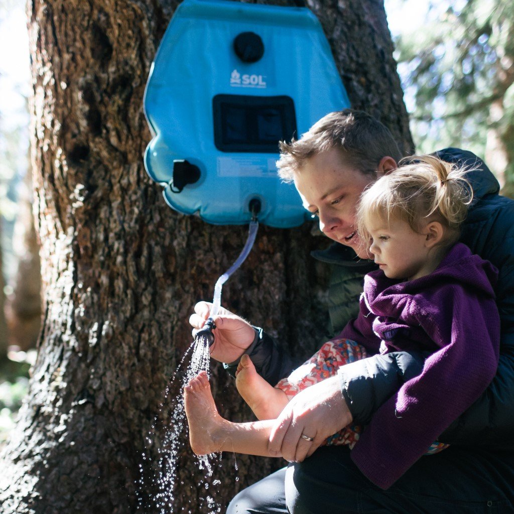Solar Shower 20L hanging on tree with man washing child's feet