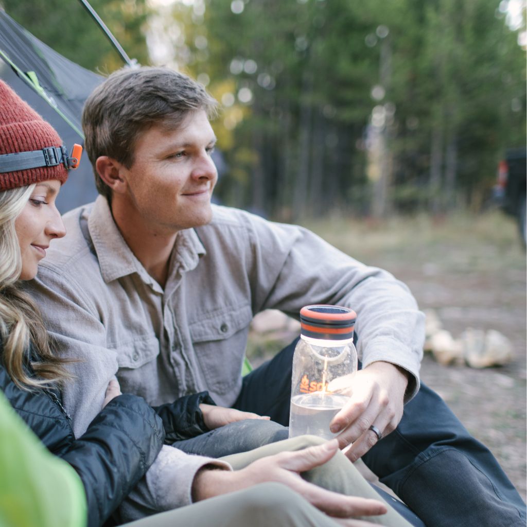 Venture Solar Water Bottle Lantern man holding seated next to woman in tent entrance while camping