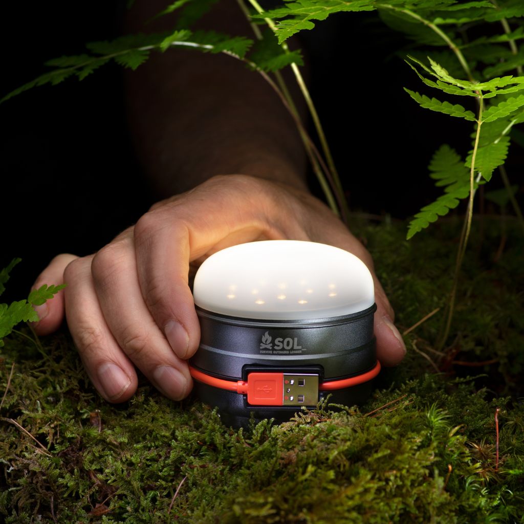 Venture Light 3000 Recharge with Power Bank holding lit Venture Light on mossy ground