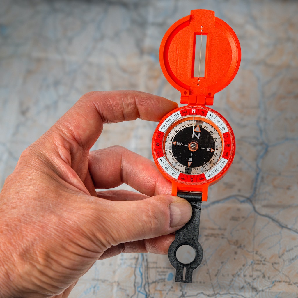 Lensatic Compass in hand in front of map