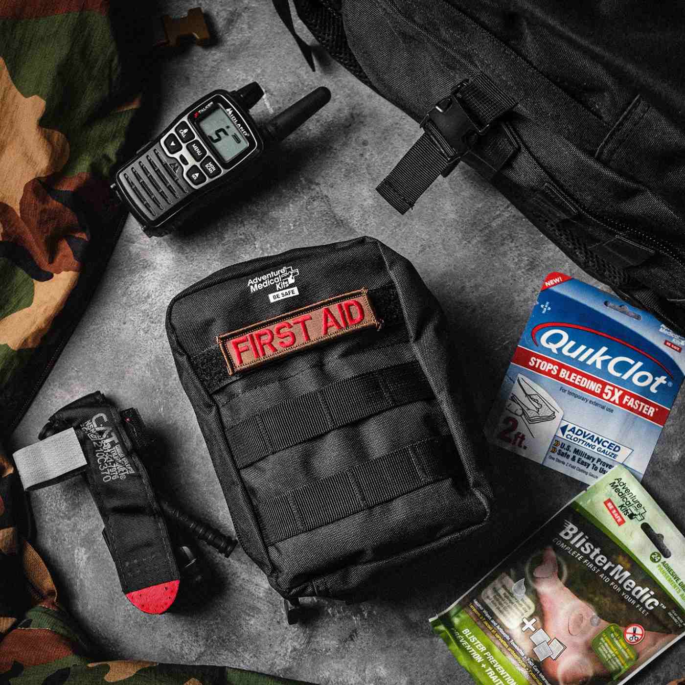 MOLLE Bag Trauma Kit 1.0 - Black with First Aid patch next to QuikClot, radio, and Blister Medic