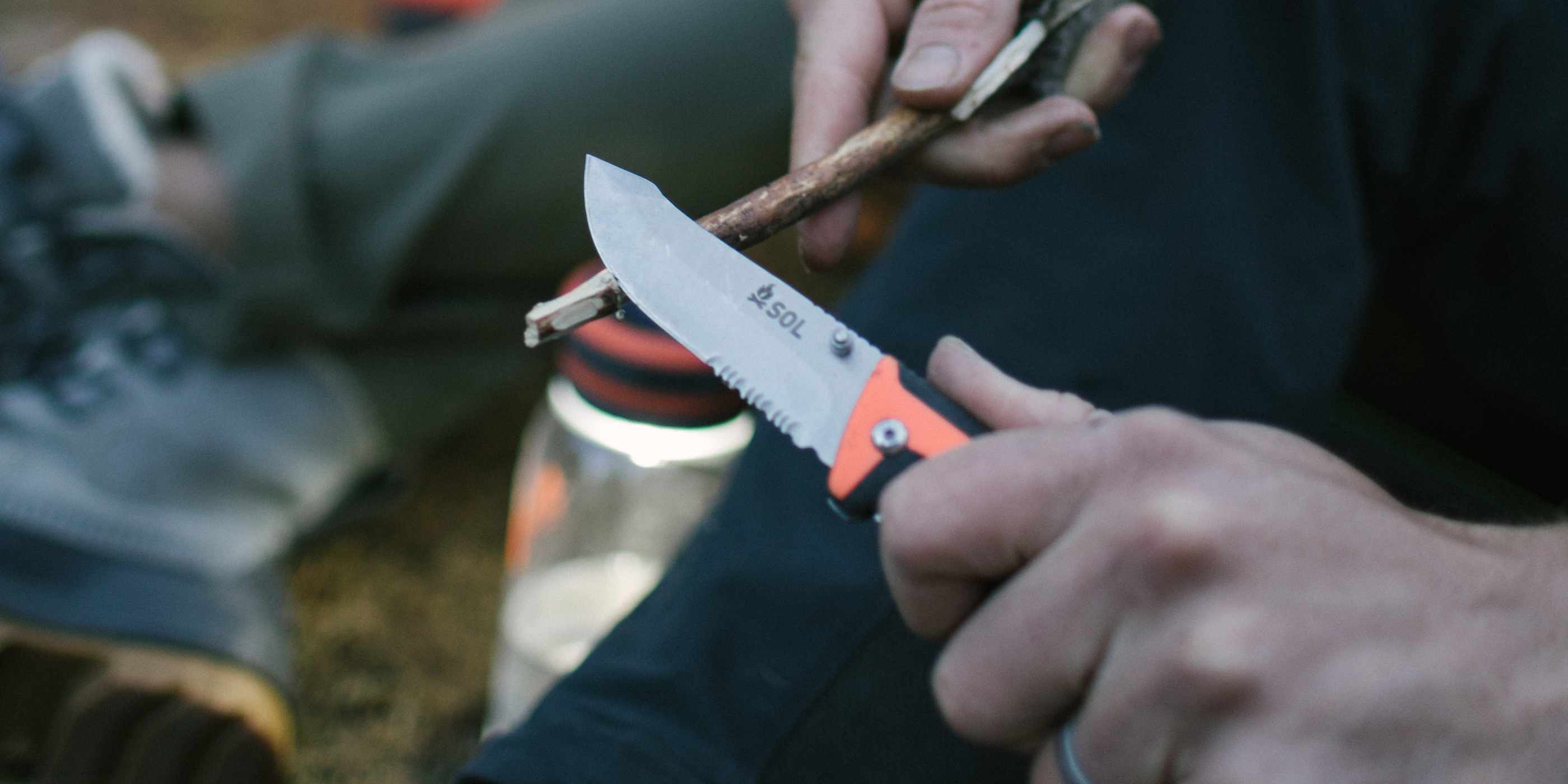 Person Using SOL Stoke Folding Knife to Shave Twig