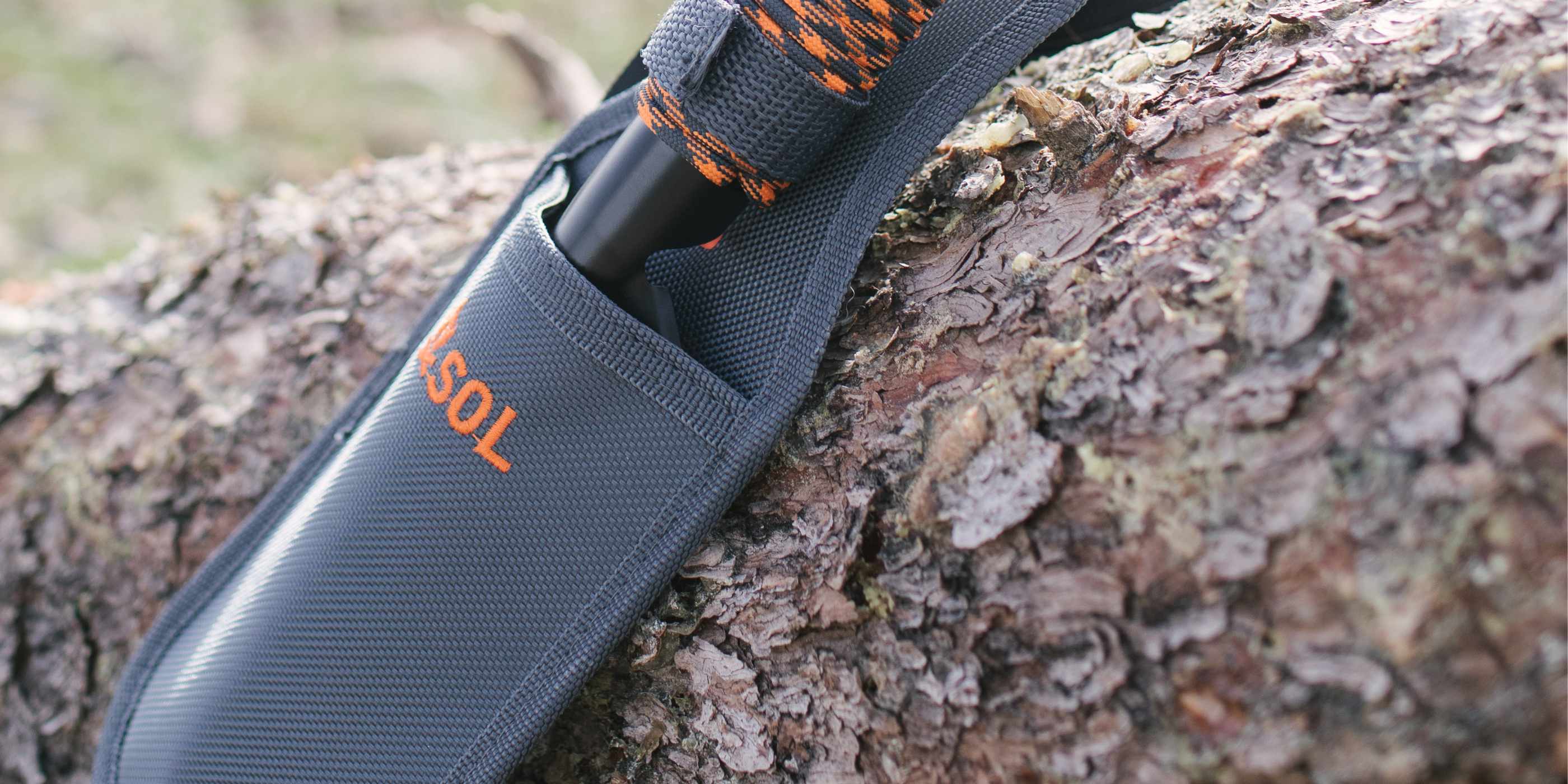 SOL Stoke Shovel in Holster Lying on a Tree