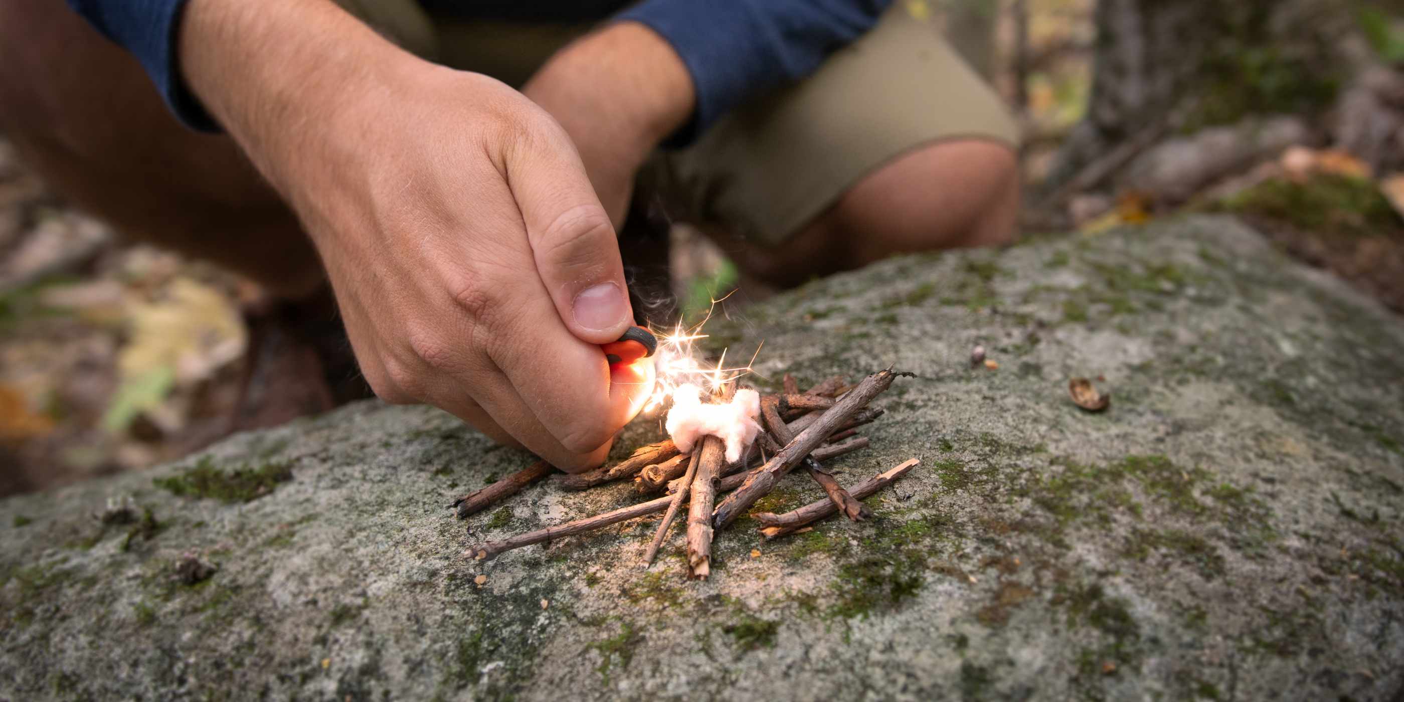 Person Lighting Tinder Quik on Rock with Twigs