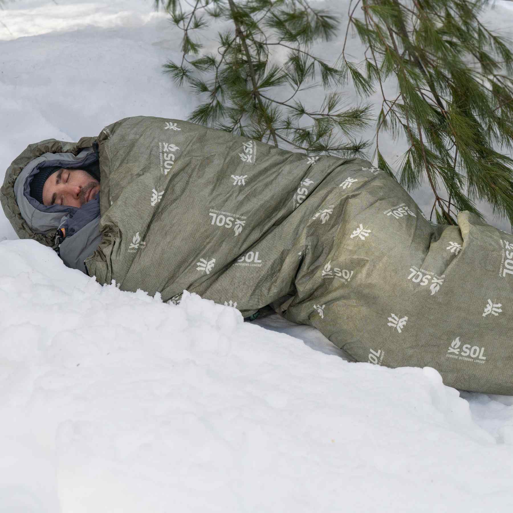 Escape Bivvy OD Green man sleeping on snow in bivvy and sleeping bag