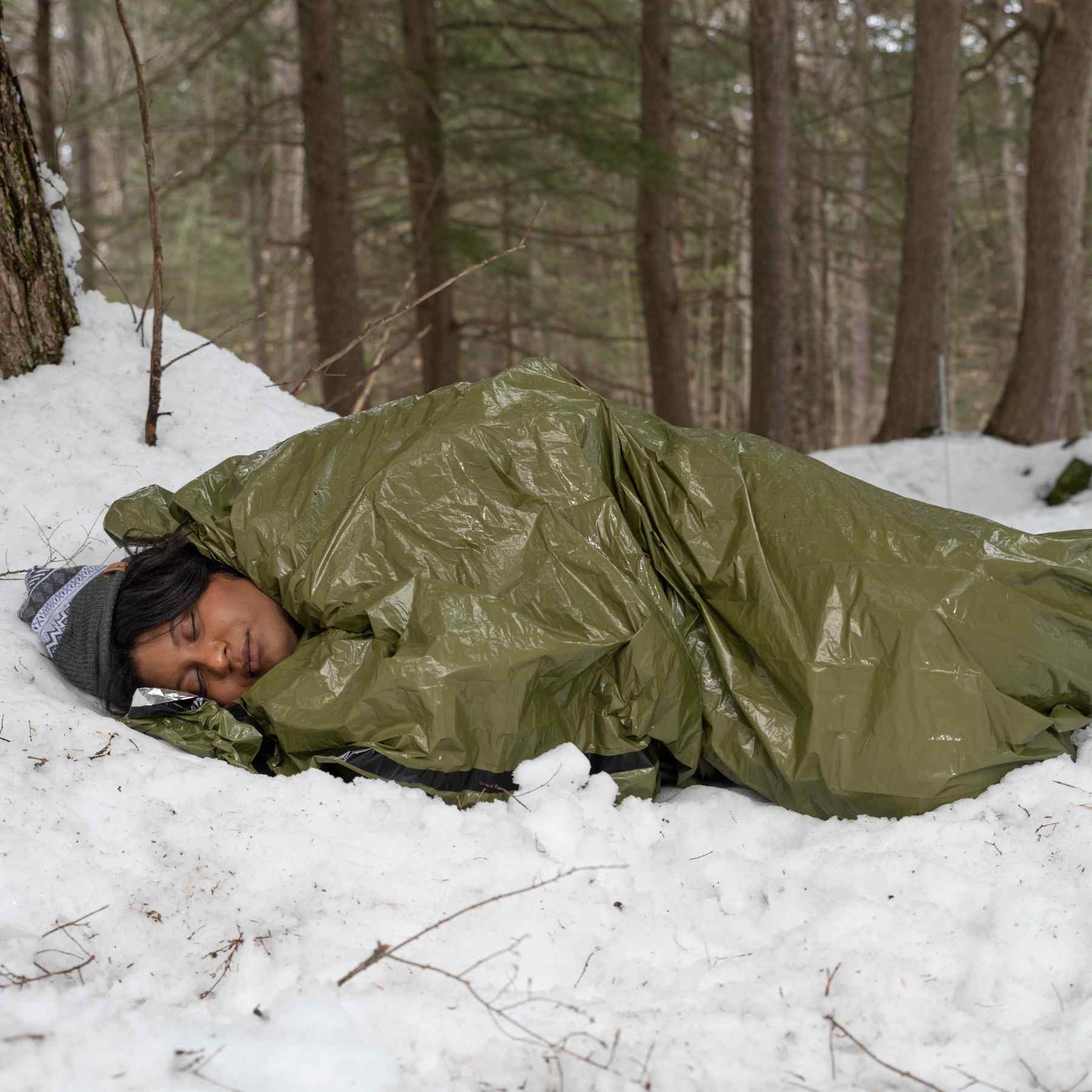 Emergency Bivvy with Rescue Whistle - OD Green woman laying in bivvy on snow