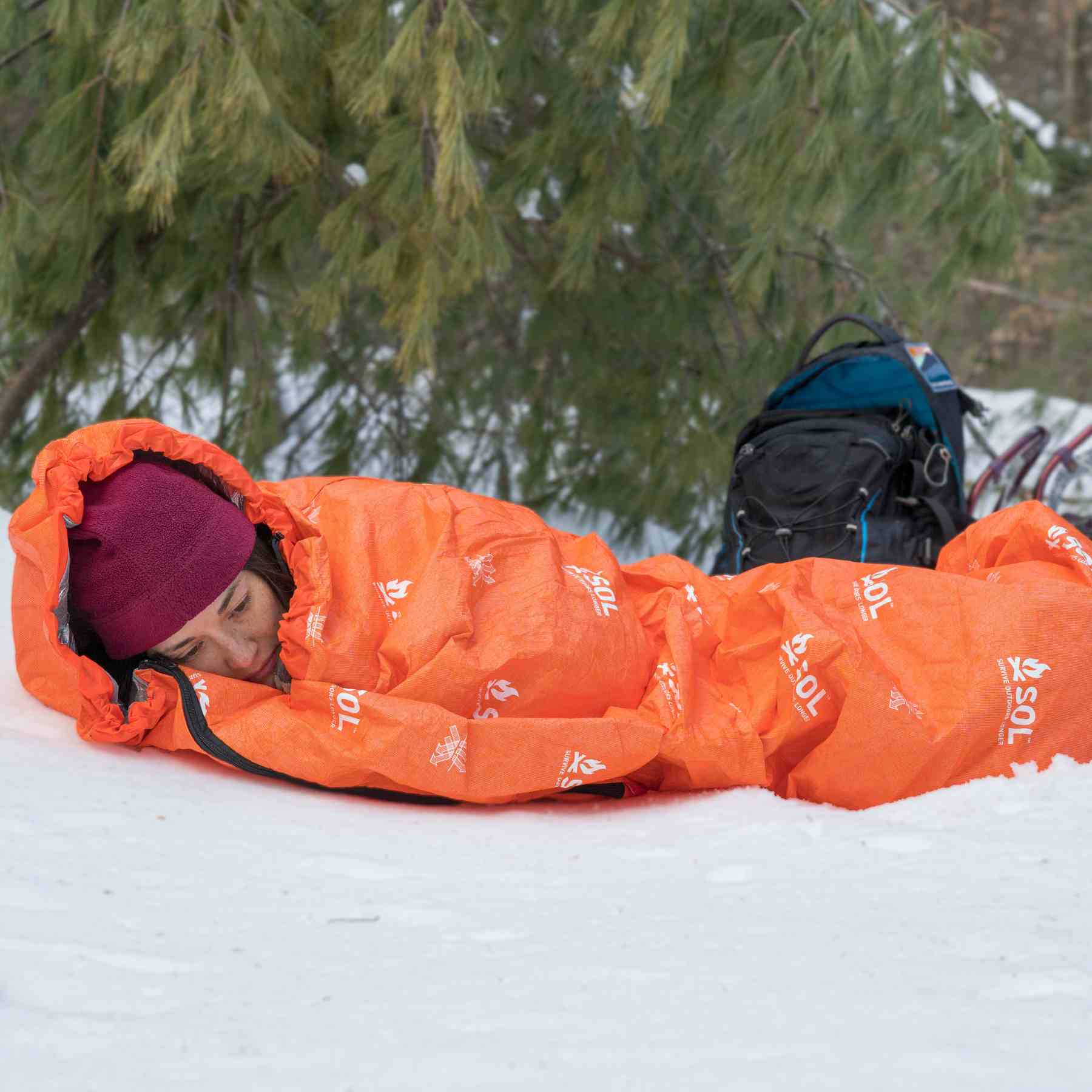 Escape Bivvy Orange woman laying in snow in bivvy