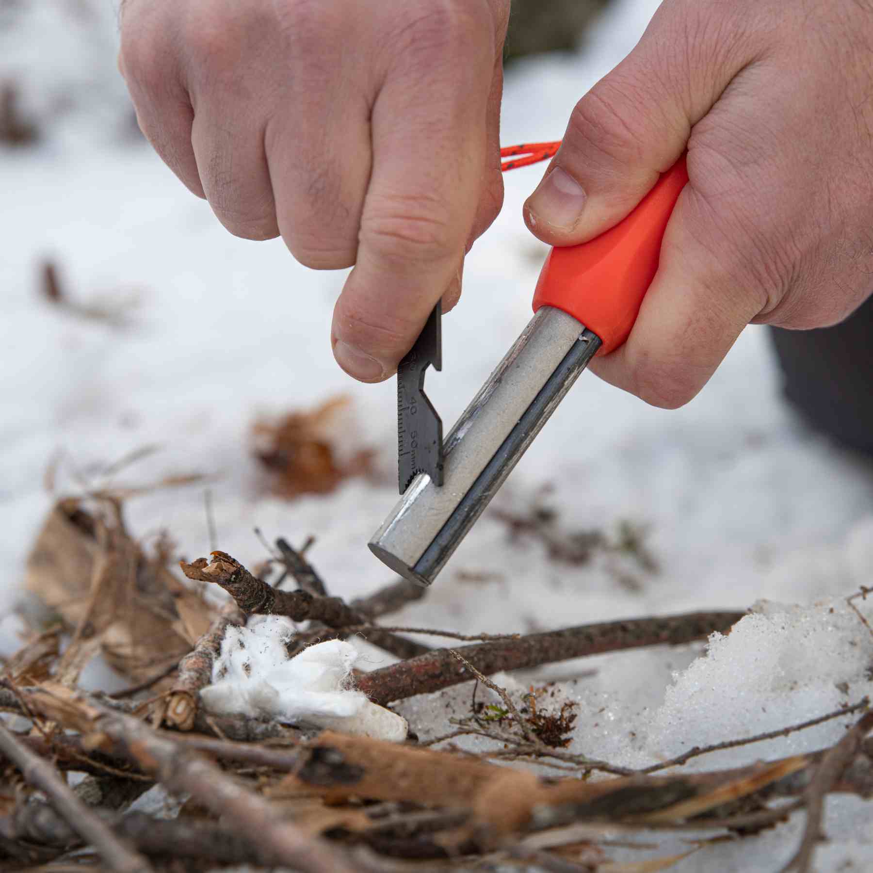 Mag Striker with Tinder Cord about to strike on twigs on snow