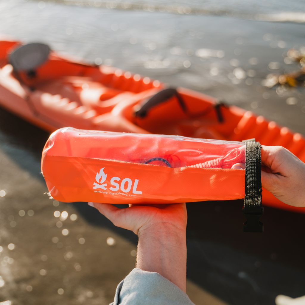Adventure Ready Survival Kit opening kit in front of kayak on water