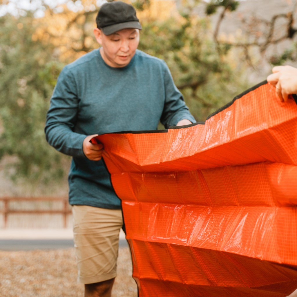 All Season Blanket man holding corner of blanket to fold