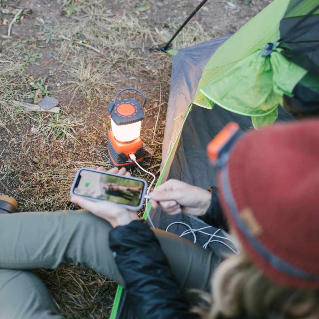 Camp Lantern Recharge with Power Bank woman sitting in tent using lantern to charge phone