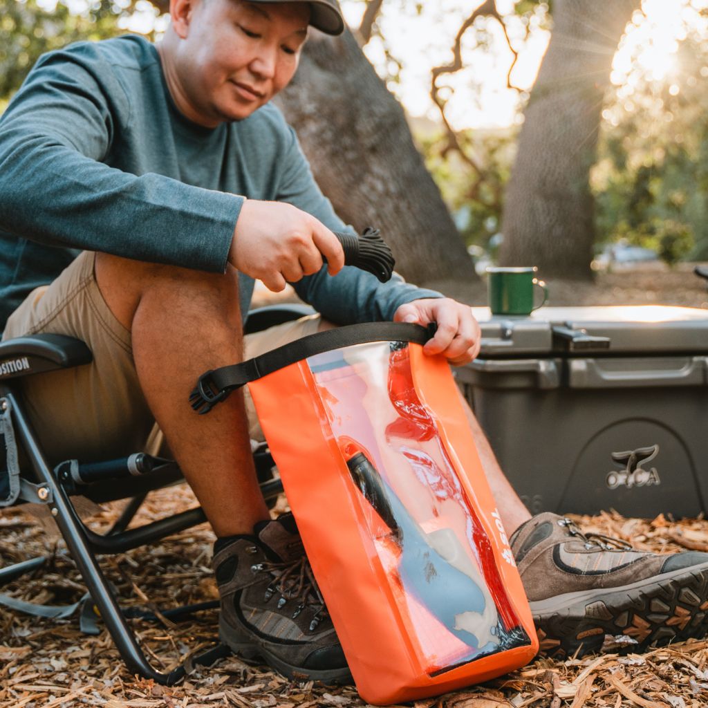 Camp Ready Survival Kit man removing paracord from kit bag while seated outside next to cooler