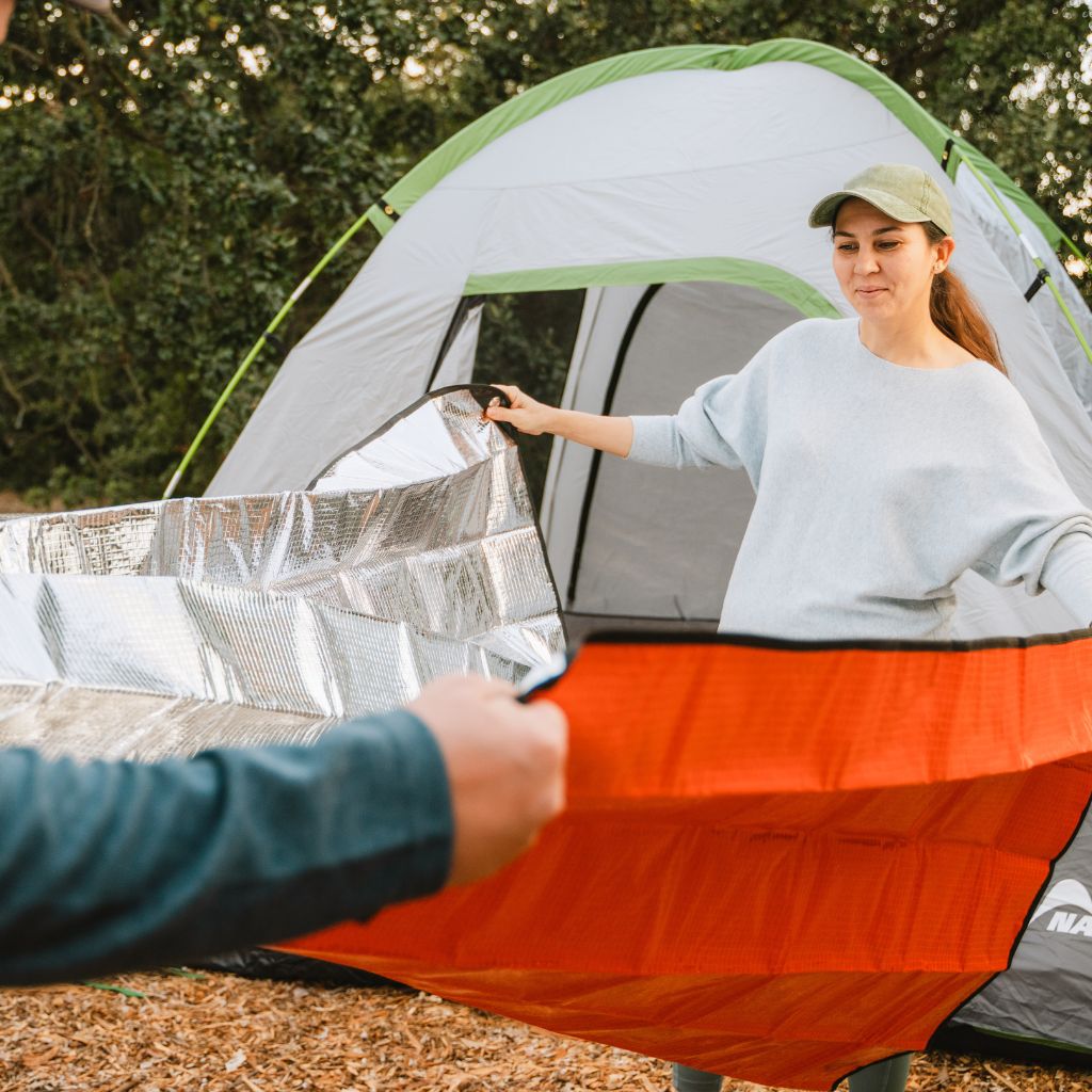 Camp Ready Survival Kit people opening up All Season Blanket in front of tent