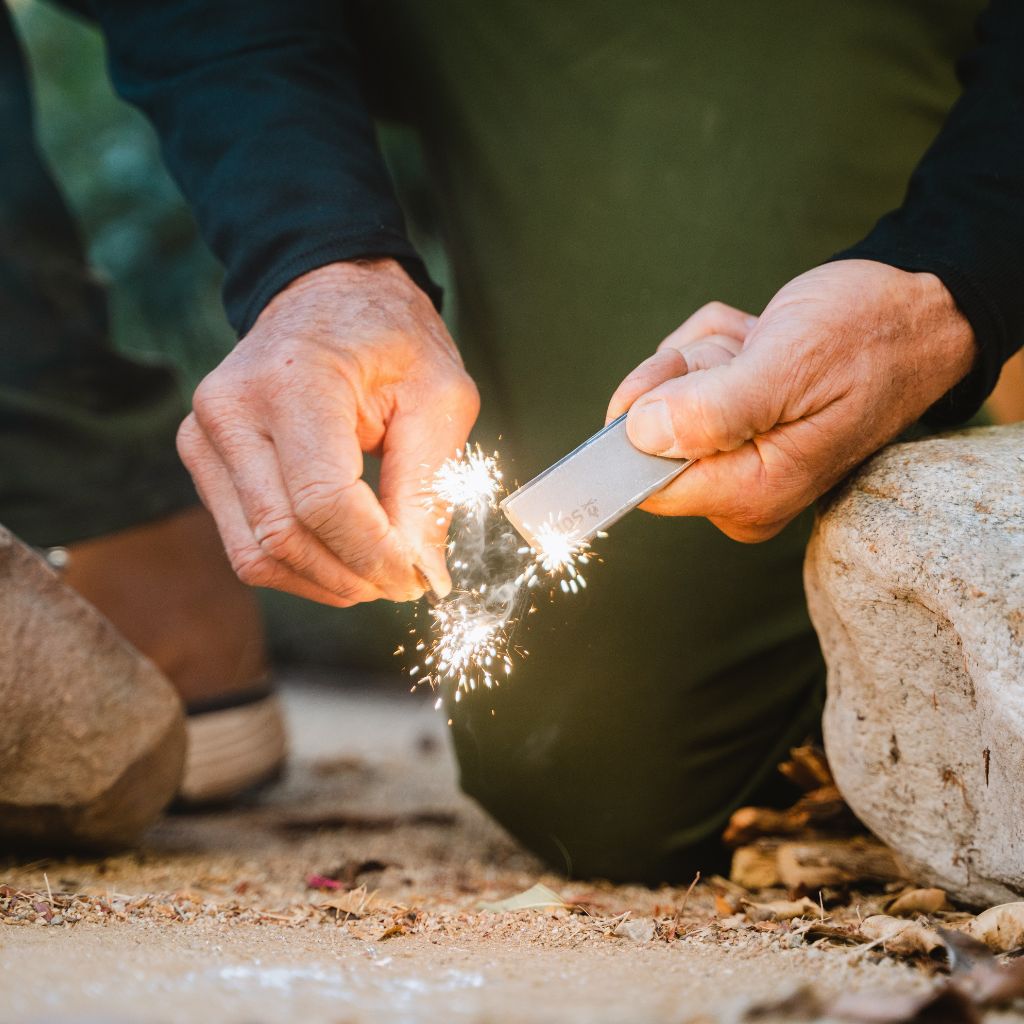 Camp Ready Survival Kit using mag block to create sparks on the ground