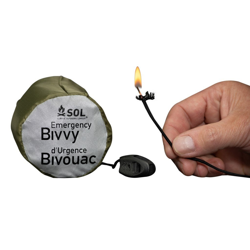 Emergency Bivvy with Rescue Whistle - OD Green tindercord lit with flame next to bivvy in sleeve