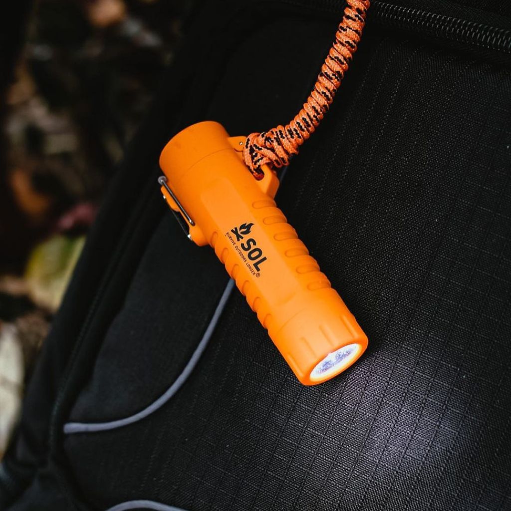 Fire Lite Fuel-Free Lighter flashlight lit while attached to black backpack