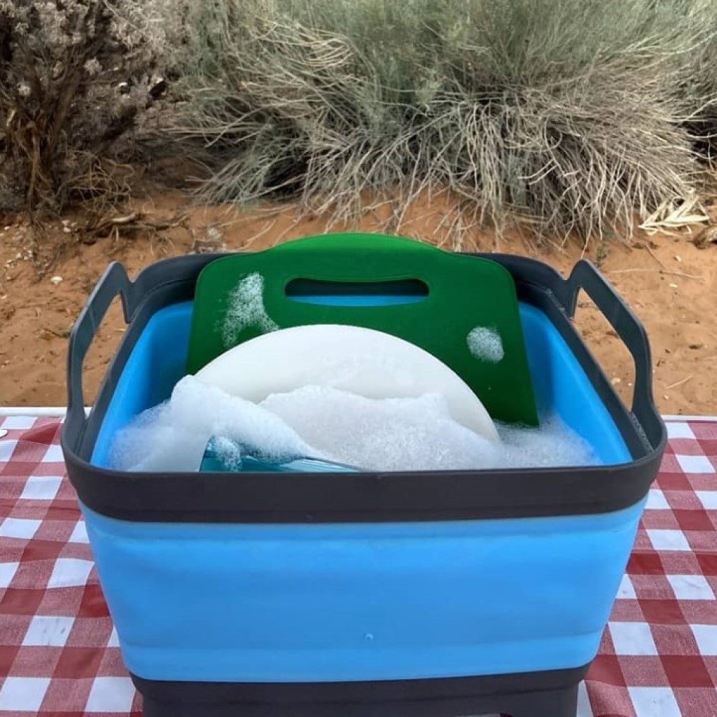 Flat Pack Sink 8L filled with dishes and water on checkered tablecloth