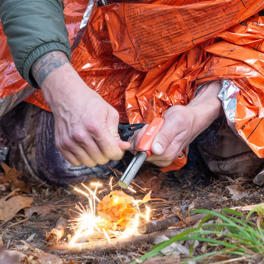 Mag Striker with Tinder Cord creating sparks wrapped in orange blanket
